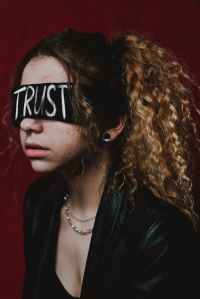 woman blindfolded with the word trust written on the blindfold